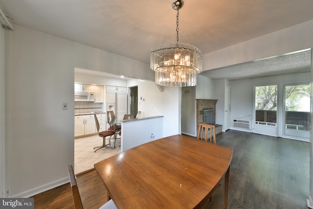 1556 Coolidge Ave, Abington, PA 19001 - unfurnished dining area with a brick fireplace, a chandelier, wood finished floors, and a wall unit AC