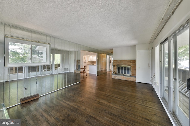 1556 Coolidge Ave, Abington, PA 19001 - unfurnished living room with a textured ceiling, wood finished floors, a brick fireplace, and a baseboard heating unit