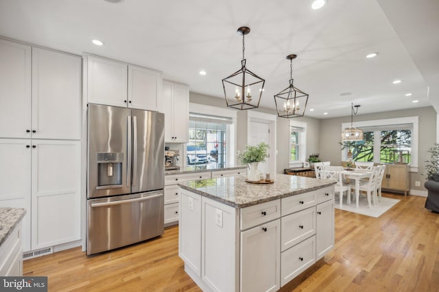 kitchen featuring stainless steel refrigerator with ice dispenser, white cabinets, and a center island