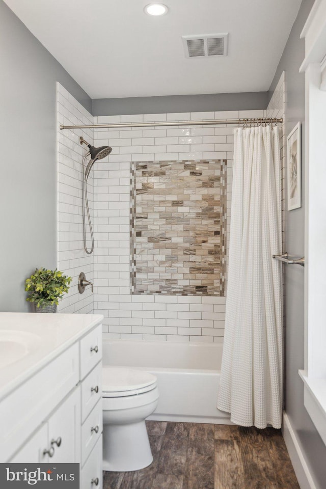 full bathroom featuring vanity, shower / tub combo with curtain, toilet, wood finished floors, and visible vents