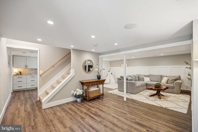 living room featuring recessed lighting, baseboards, wood finished floors, and stairway