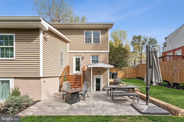 back of property with fence, a patio, a lawn, and an outdoor fire pit
