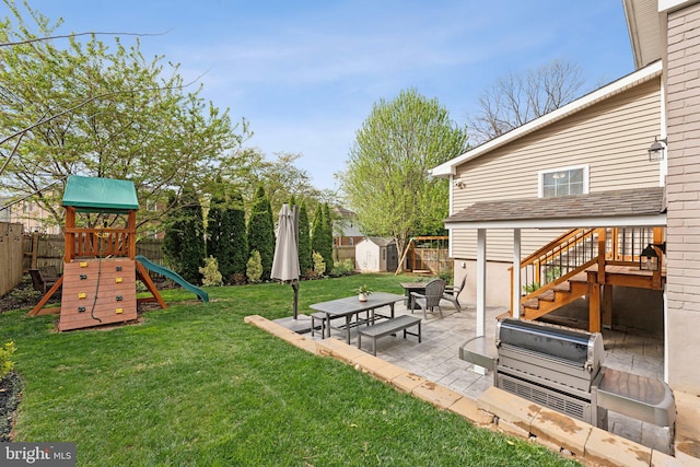 view of yard with a storage unit, a fenced backyard, an outbuilding, a playground, and a patio
