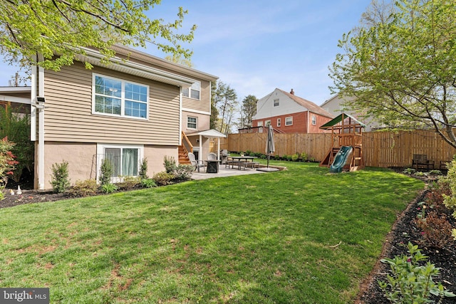 rear view of property featuring a playground, a patio area, fence, and a yard