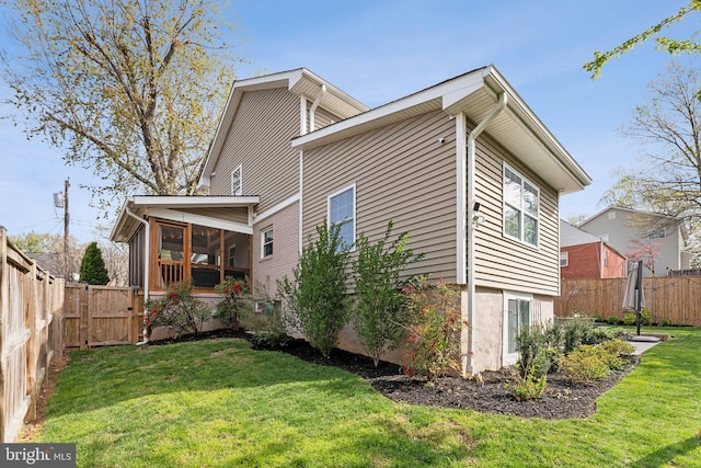 view of property exterior with a fenced backyard, a yard, and a sunroom