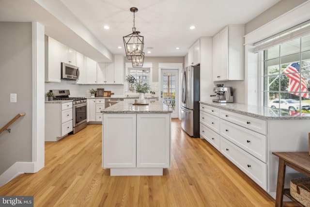 kitchen featuring a center island, white cabinetry, appliances with stainless steel finishes, and a healthy amount of sunlight