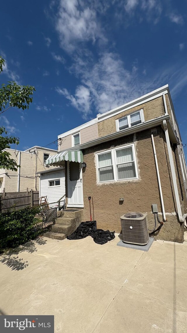 6707 Ditman St, Philadelphia, PA 19135 - back of property featuring fence, stucco siding, cooling unit, and a patio