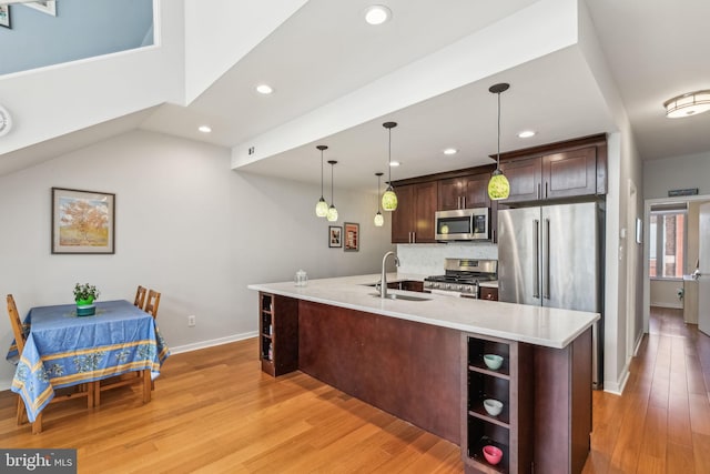 kitchen with a sink, dark brown cabinetry, light wood finished floors, appliances with stainless steel finishes, and recessed lighting