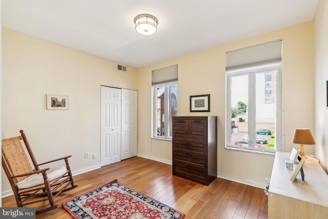 sitting room with baseboards, light wood finished floors, and visible vents