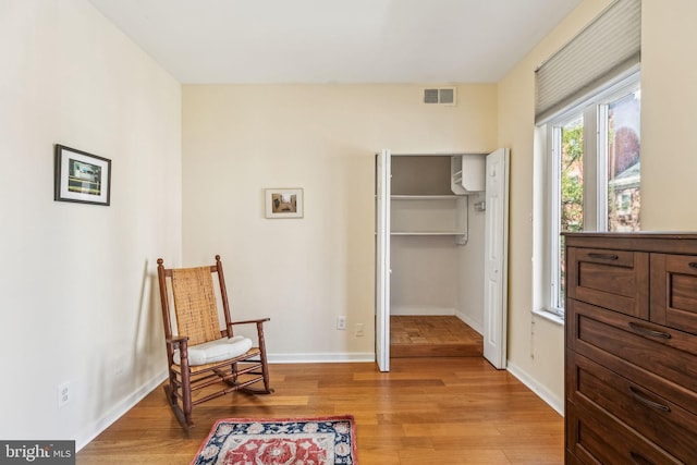 living area featuring visible vents, light wood finished floors, and baseboards