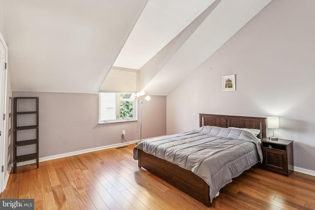 bedroom with lofted ceiling, light wood-style flooring, baseboards, and visible vents