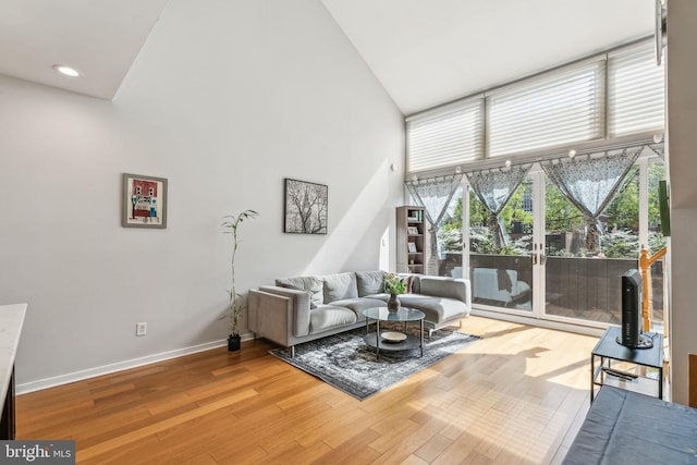 living area with high vaulted ceiling, baseboards, wood finished floors, and recessed lighting