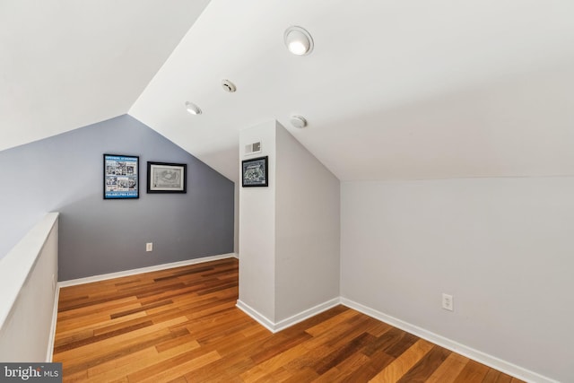 bonus room featuring lofted ceiling, visible vents, baseboards, and wood finished floors