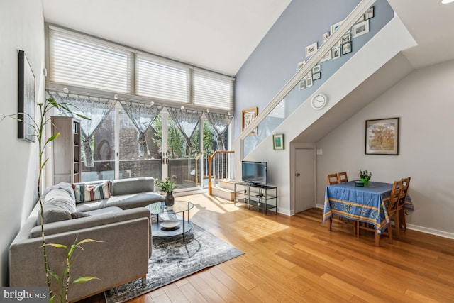 living room featuring high vaulted ceiling, baseboards, and hardwood / wood-style flooring