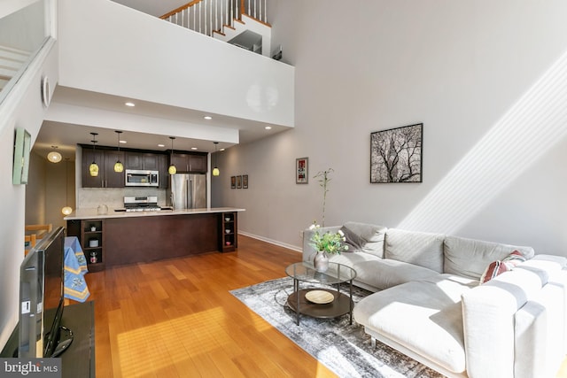 living room featuring baseboards, a high ceiling, and light wood-type flooring