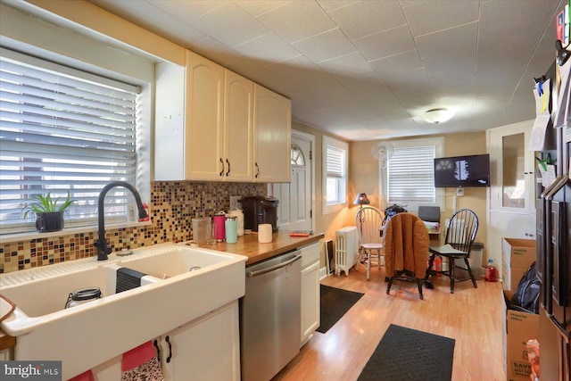 kitchen featuring tasteful backsplash, white cabinets, a sink, stainless steel dishwasher, and light wood-style flooring