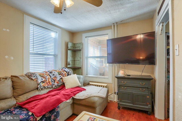 living area with a healthy amount of sunlight, a textured ceiling, a ceiling fan, and wood finished floors