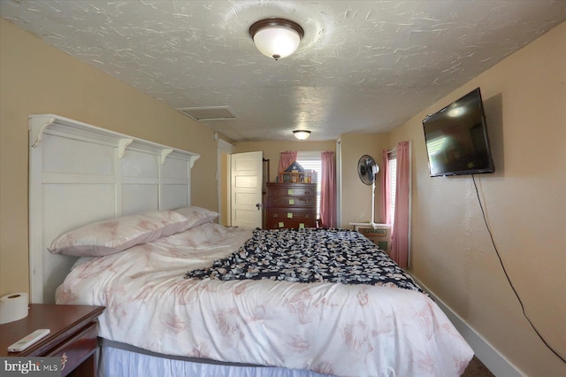 bedroom with a textured ceiling and attic access