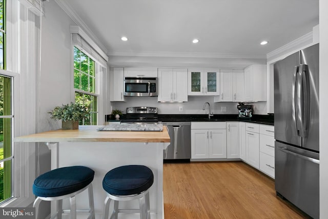 10945 Harpers Square Ct, Reston, VA 20191 - kitchen with appliances with stainless steel finishes, butcher block counters, a breakfast bar, crown molding, and white cabinetry
