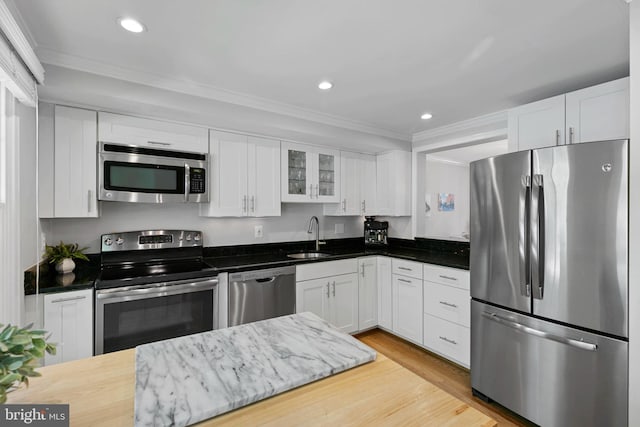 10945 Harpers Square Ct, Reston, VA 20191 - kitchen with stainless steel appliances, a sink, ornamental molding, white cabinetry, and light wood-style flooring