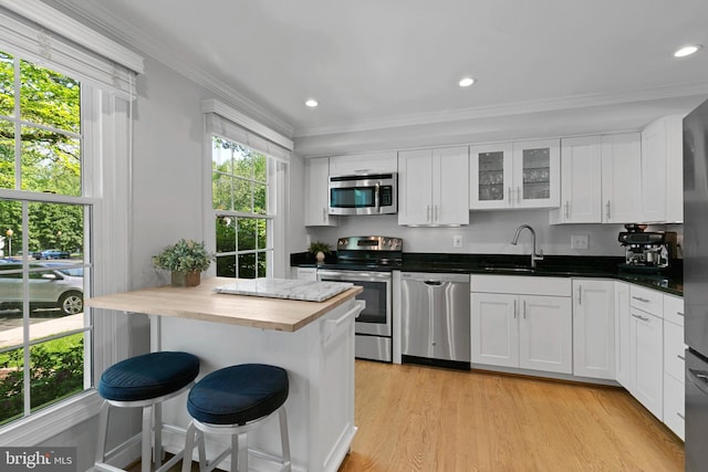 10945 Harpers Square Ct, Reston, VA 20191 - kitchen featuring stainless steel appliances, a breakfast bar, crown molding, white cabinetry, and glass insert cabinets