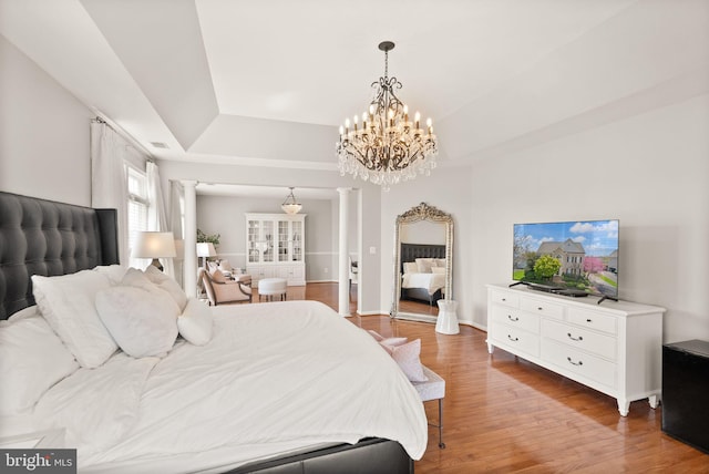 43005 Running Ridge Way, Leesburg, VA 20176 - bedroom featuring ornate columns, a raised ceiling, wood finished floors, and a chandelier