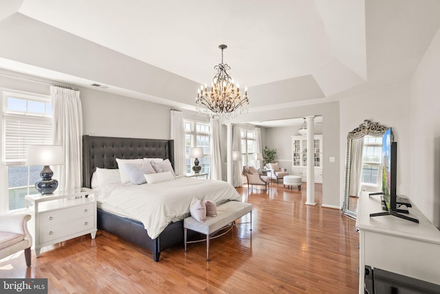 43005 Running Ridge Way, Leesburg, VA 20176 - bedroom with ornate columns, a chandelier, light wood-style flooring, and a tray ceiling