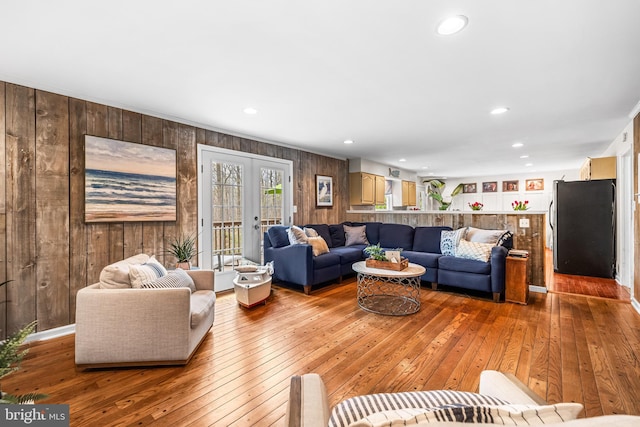 living room with recessed lighting, wooden walls, french doors, and hardwood / wood-style floors
