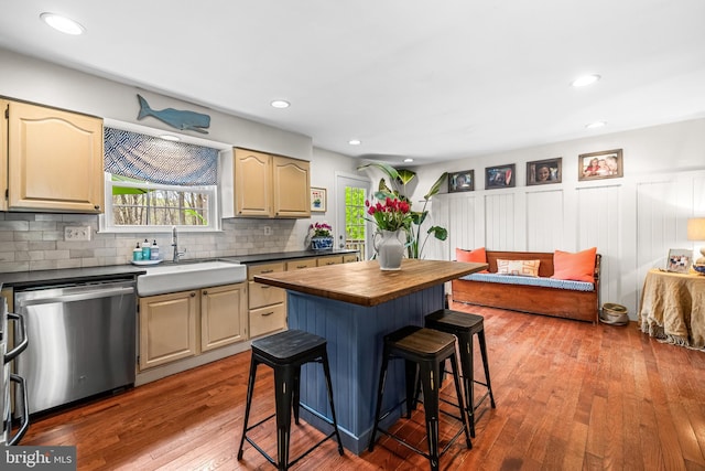 kitchen with plenty of natural light, a sink, wooden counters, a kitchen breakfast bar, and stainless steel dishwasher