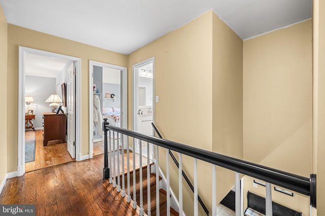 hall with an upstairs landing, baseboards, a sink, and wood finished floors