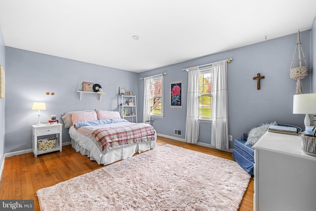 bedroom with visible vents, baseboards, and wood finished floors
