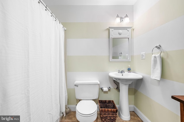 full bathroom featuring toilet, a sink, and baseboards