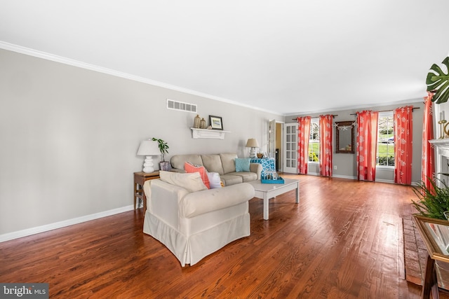 living area with visible vents, baseboards, a fireplace, crown molding, and wood finished floors