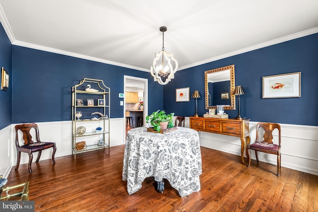 dining space with crown molding, a notable chandelier, and wainscoting