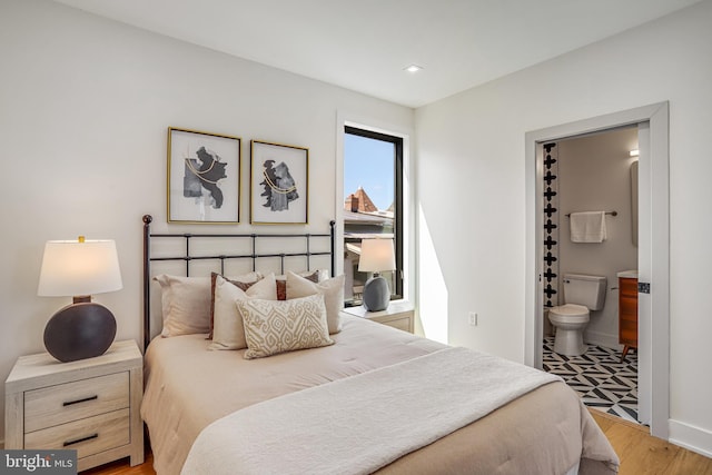 bedroom featuring light wood-style flooring, ensuite bathroom, baseboards, and recessed lighting