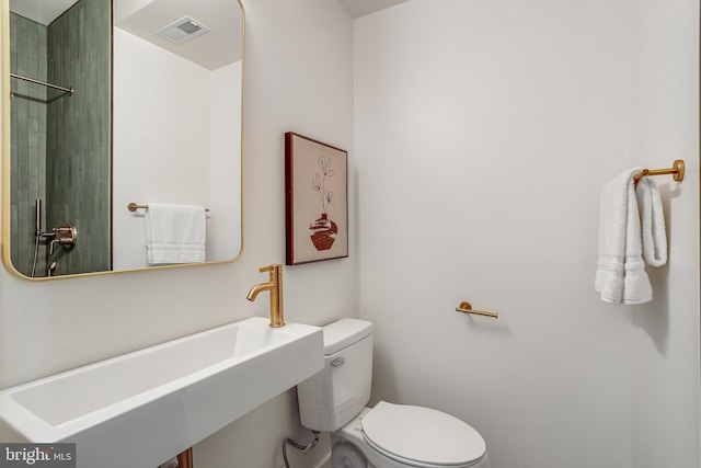 bathroom with toilet, a sink, and visible vents