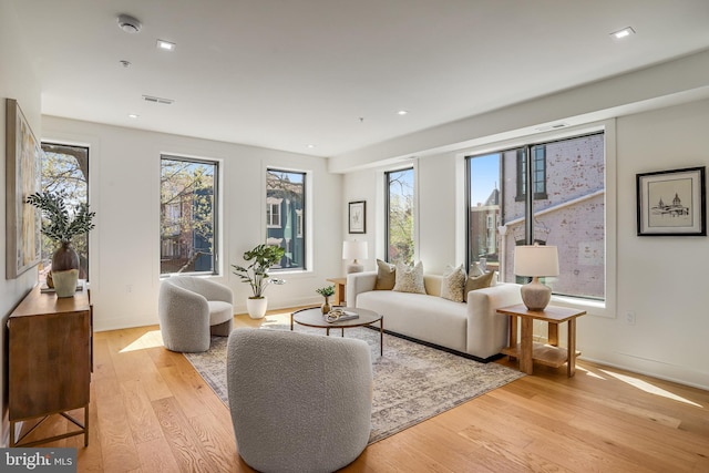 living room with light wood-style flooring, baseboards, visible vents, and recessed lighting