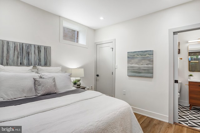 bedroom featuring recessed lighting, ensuite bathroom, baseboards, and wood finished floors