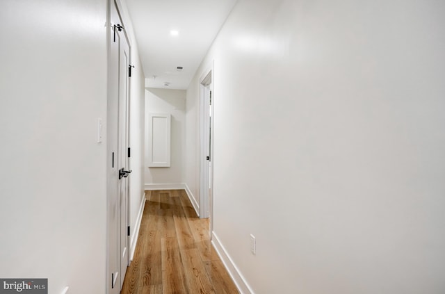 corridor with light wood-type flooring and baseboards