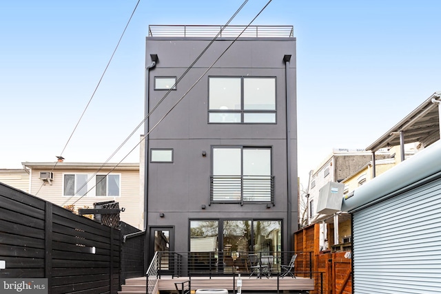 rear view of property featuring stucco siding and fence