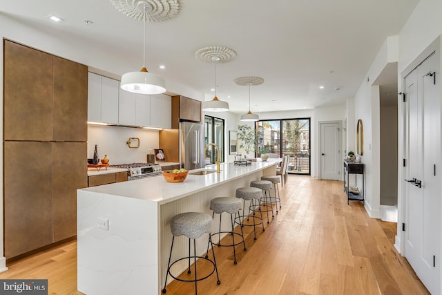 kitchen featuring a breakfast bar, light countertops, light wood-style floors, stainless steel appliances, and a sink