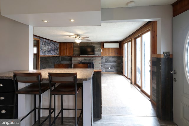 2447 General Potter Hwy, Centre Hall, PA 16828 - kitchen with a ceiling fan, a fireplace, a kitchen breakfast bar, wood walls, and recessed lighting