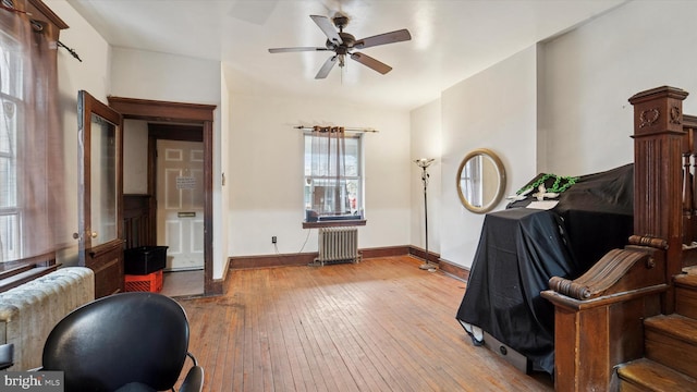interior space with ceiling fan, radiator heating unit, wood-type flooring, and baseboards