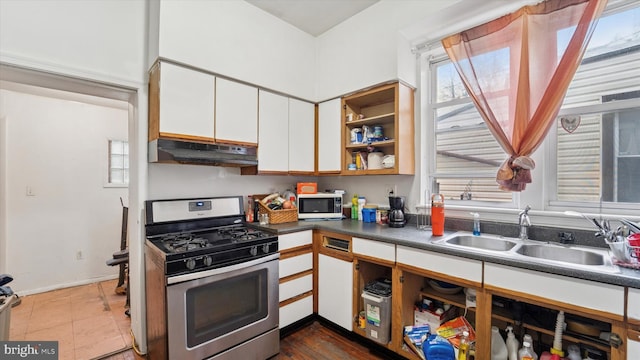 kitchen featuring white cabinetry, under cabinet range hood, gas stove, a sink, and plenty of natural light