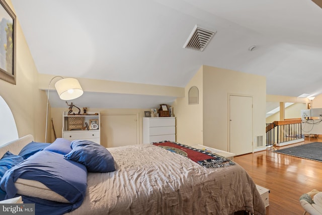 bedroom with visible vents, vaulted ceiling, and wood finished floors
