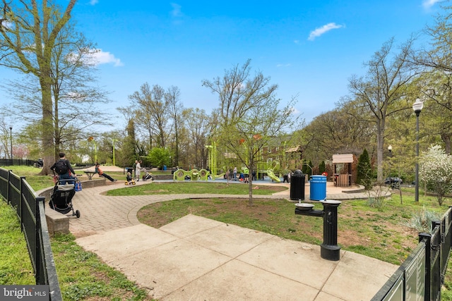 view of property's community with playground community, fence, and a lawn