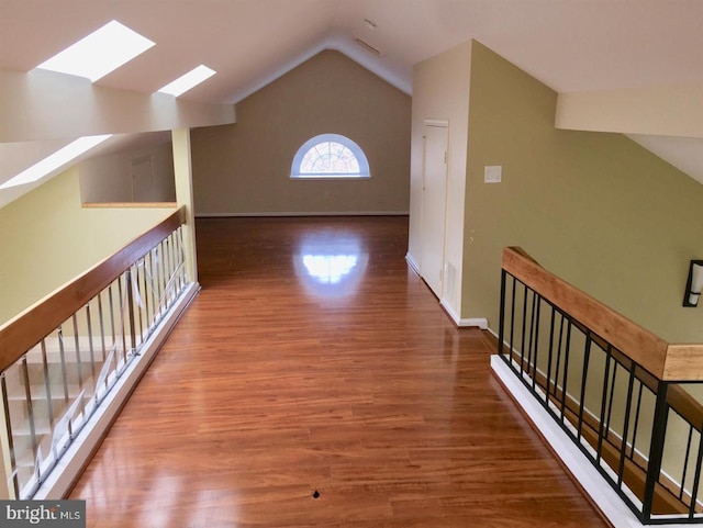 additional living space with baseboards, lofted ceiling with skylight, and wood finished floors