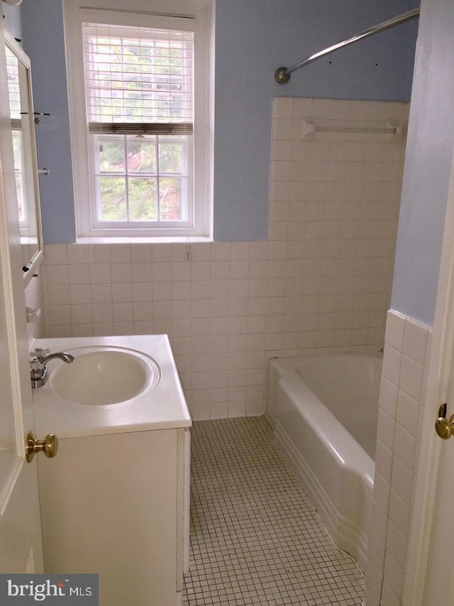 full bathroom with vanity, shower / washtub combination, tile patterned floors, wainscoting, and tile walls