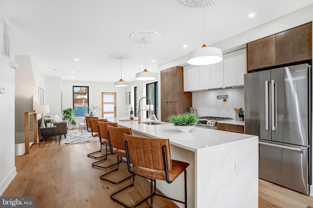 kitchen with modern cabinets, a kitchen breakfast bar, appliances with stainless steel finishes, light countertops, and light wood finished floors