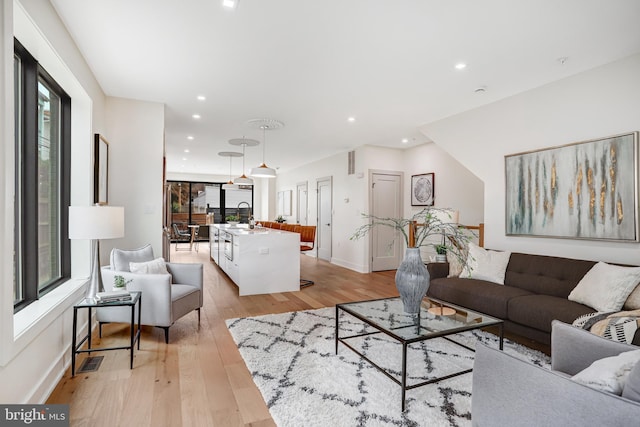 living room featuring recessed lighting, visible vents, light wood-type flooring, and baseboards